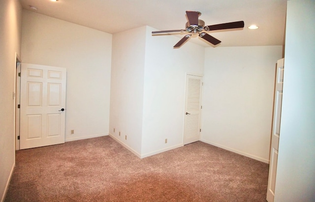 carpeted spare room with ceiling fan and lofted ceiling