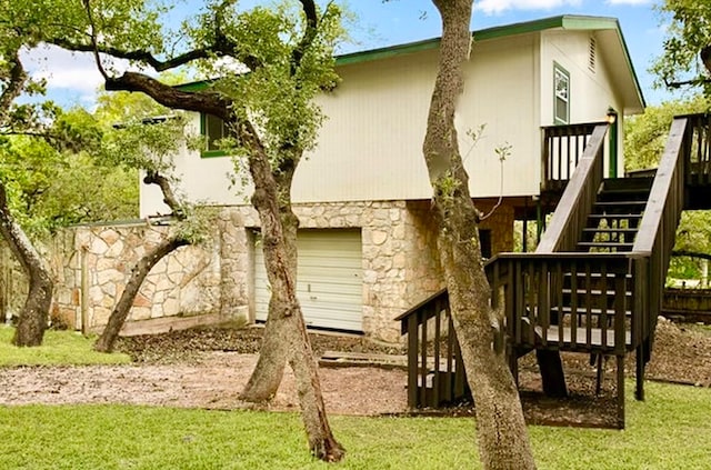 rear view of property with a yard, a wooden deck, and a garage