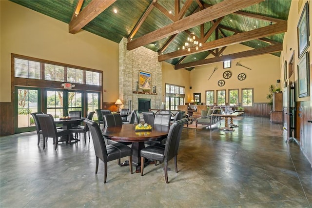 dining area with beamed ceiling, high vaulted ceiling, a fireplace, and a notable chandelier