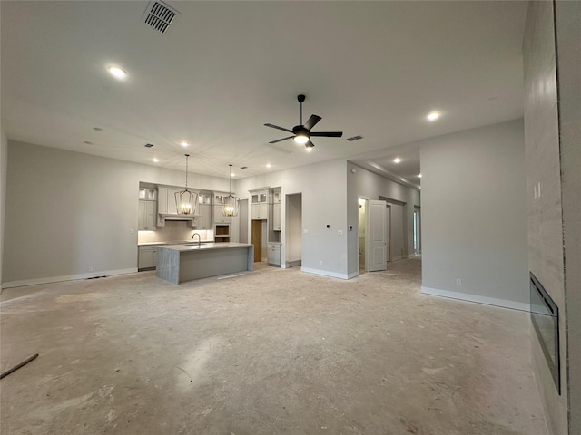 unfurnished living room featuring ceiling fan and sink