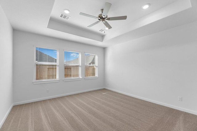 carpeted spare room featuring ceiling fan and a raised ceiling