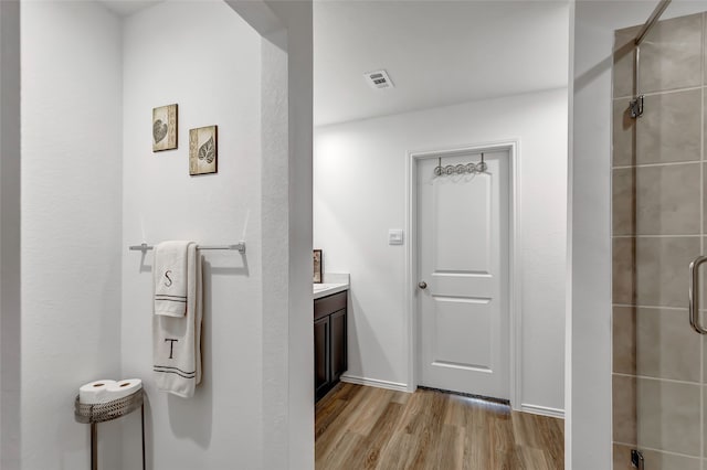 bathroom featuring wood-type flooring, vanity, and a shower with door