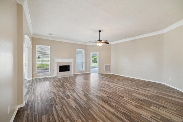 unfurnished living room with ceiling fan, dark wood-type flooring, ornamental molding, and a fireplace