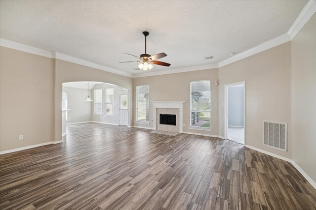 unfurnished living room with dark wood-type flooring, ornamental molding, plenty of natural light, and ceiling fan