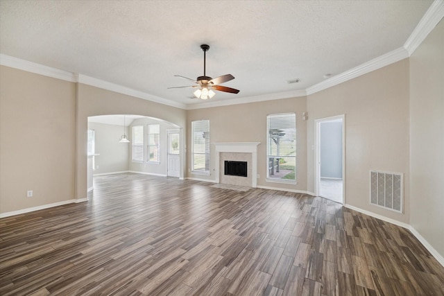 unfurnished living room with crown molding, ceiling fan, dark hardwood / wood-style floors, a textured ceiling, and a tiled fireplace