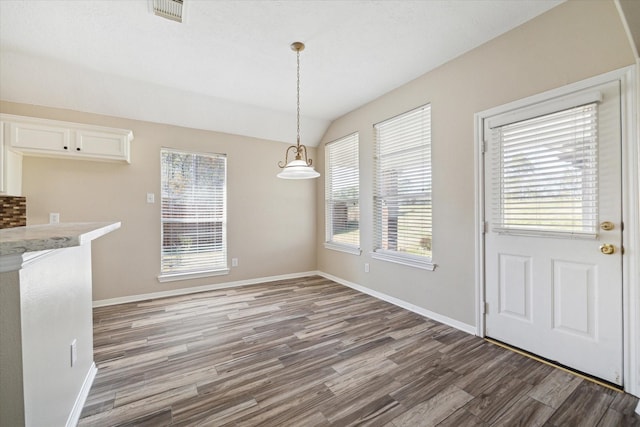 unfurnished dining area featuring wood-type flooring and vaulted ceiling