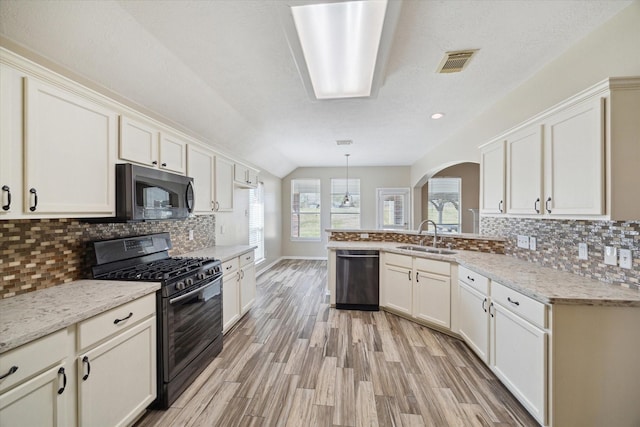 kitchen with black gas range oven, dishwashing machine, pendant lighting, light stone counters, and sink