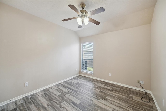 empty room with vaulted ceiling, ceiling fan, a textured ceiling, and hardwood / wood-style flooring