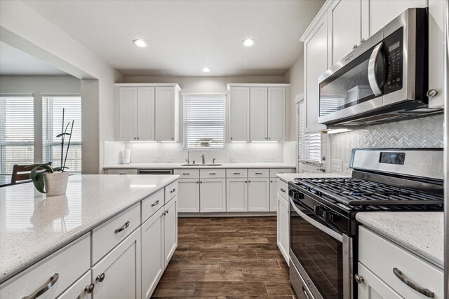 kitchen featuring white cabinets, appliances with stainless steel finishes, dark hardwood / wood-style floors, and a healthy amount of sunlight