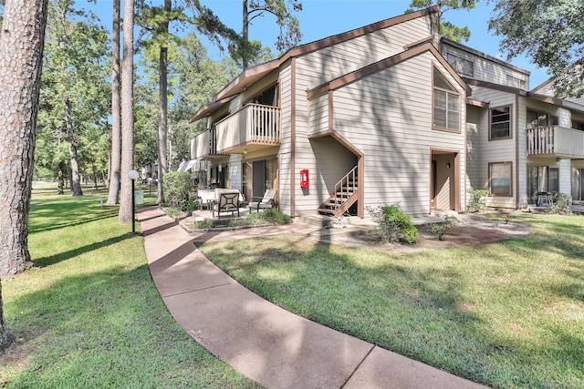 exterior space featuring a balcony, a yard, and a patio