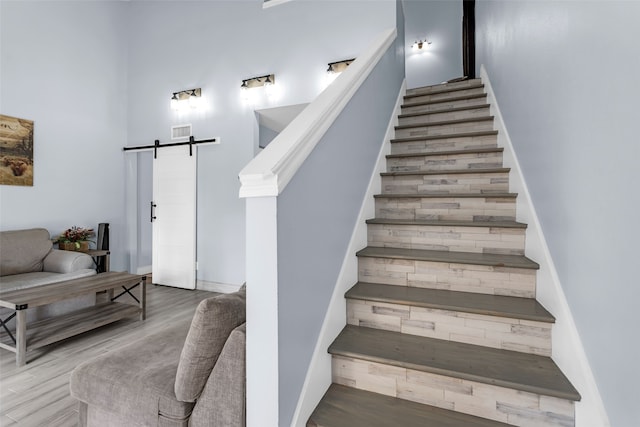 stairway with a barn door and hardwood / wood-style floors