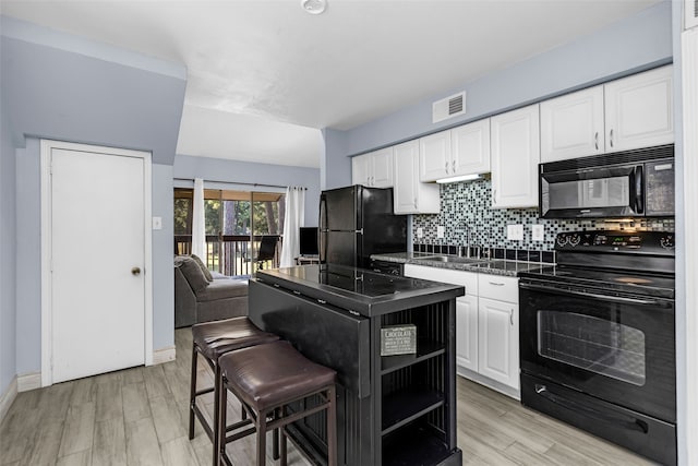 kitchen featuring black appliances, light hardwood / wood-style floors, white cabinetry, a kitchen breakfast bar, and backsplash