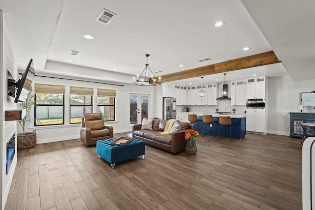 living room featuring beam ceiling, dark hardwood / wood-style flooring, and a chandelier