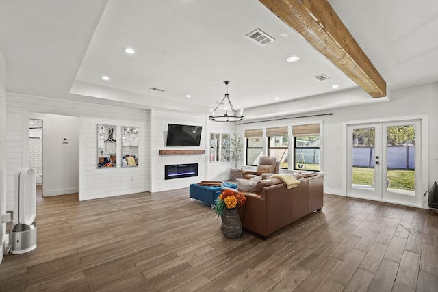 living room with beamed ceiling, french doors, a fireplace, and a chandelier