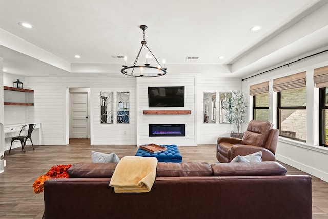 living room featuring hardwood / wood-style floors, wood walls, a fireplace, and a chandelier