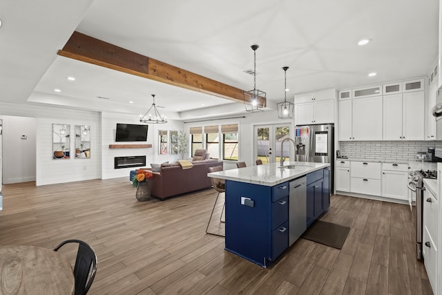 kitchen with white cabinets, decorative light fixtures, blue cabinets, and a kitchen island with sink