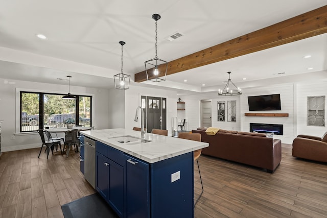 kitchen with sink, decorative light fixtures, blue cabinets, and an island with sink