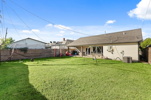 rear view of property featuring a lawn and cooling unit