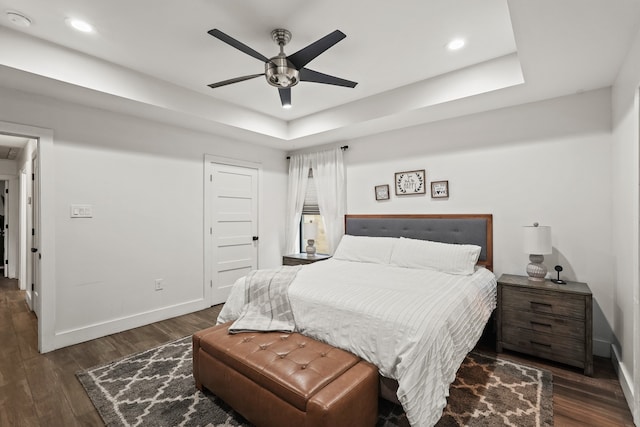 bedroom featuring ceiling fan, dark hardwood / wood-style floors, and a raised ceiling