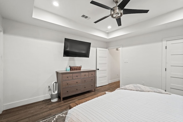 bedroom with a tray ceiling, ceiling fan, and dark hardwood / wood-style floors