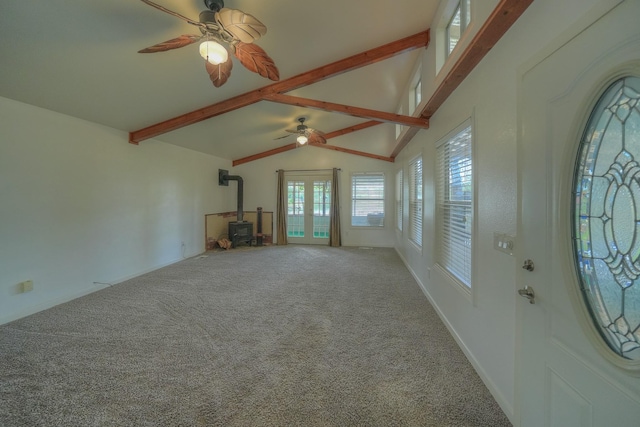 unfurnished living room with vaulted ceiling with beams, carpet flooring, a ceiling fan, baseboards, and a wood stove