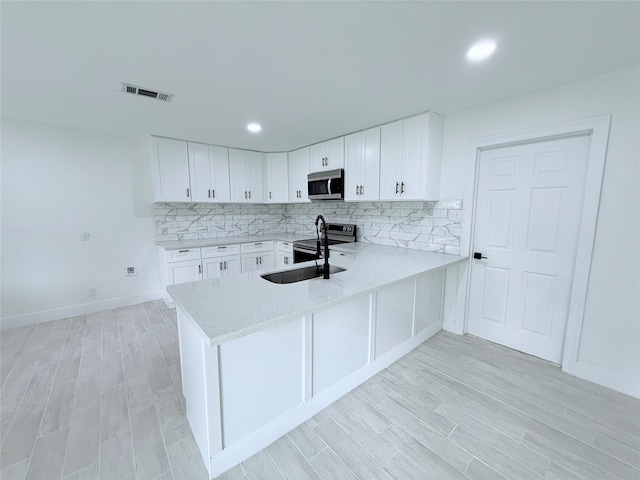 kitchen featuring white cabinets, appliances with stainless steel finishes, and light hardwood / wood-style floors