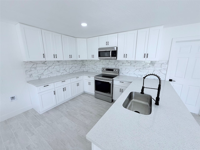 kitchen featuring sink, light hardwood / wood-style flooring, white cabinetry, stainless steel appliances, and decorative backsplash