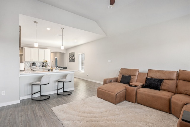 living room with light wood-type flooring, ceiling fan, and vaulted ceiling