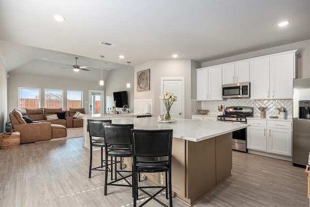 kitchen with stainless steel appliances, lofted ceiling, a spacious island, and white cabinetry