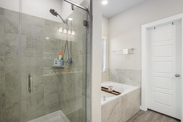 bathroom with wood-type flooring and shower with separate bathtub