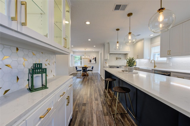 kitchen with pendant lighting, dark hardwood / wood-style flooring, white cabinetry, and backsplash