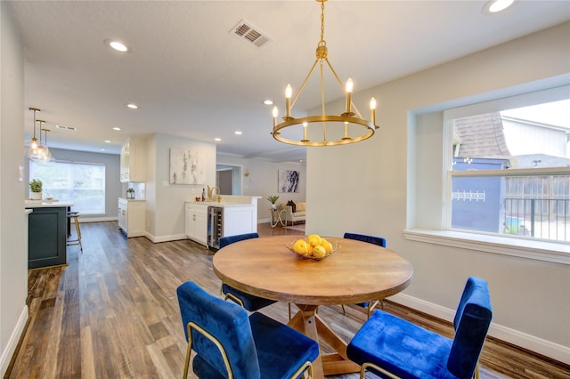 dining area with a chandelier, hardwood / wood-style flooring, and beverage cooler