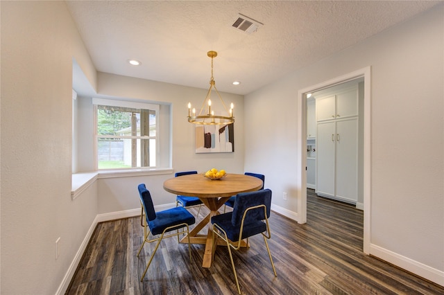 dining room with a textured ceiling, dark hardwood / wood-style floors, and an inviting chandelier