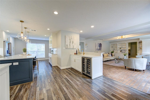 kitchen featuring dark hardwood / wood-style flooring, decorative light fixtures, white cabinetry, and a center island with sink