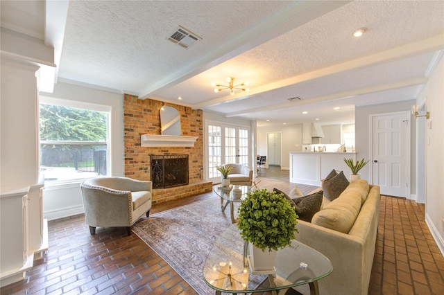 living room featuring beamed ceiling, a textured ceiling, and a brick fireplace