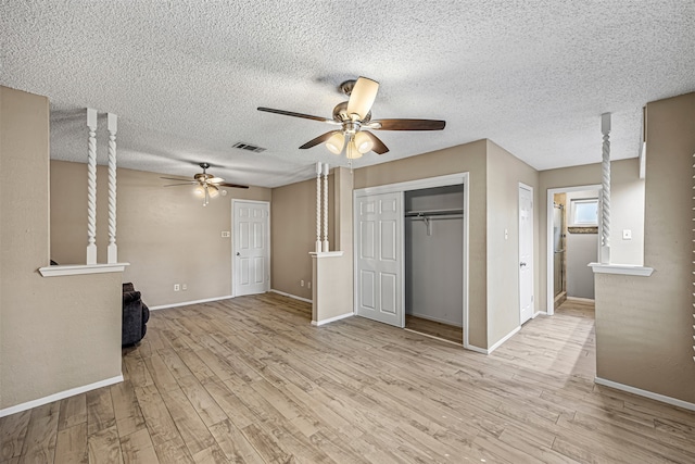 unfurnished living room featuring ceiling fan, light wood-type flooring, and a textured ceiling