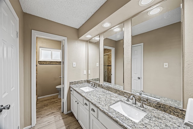 bathroom featuring hardwood / wood-style floors, vanity, an enclosed shower, toilet, and a textured ceiling