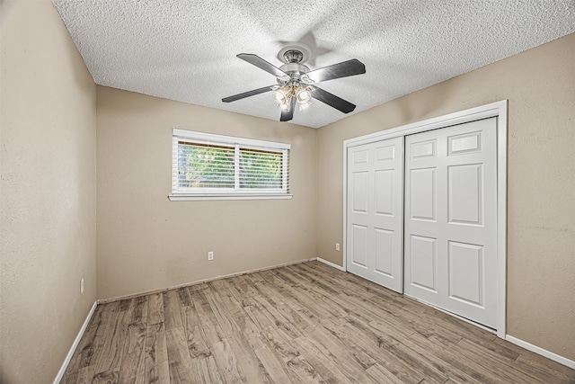 unfurnished bedroom with ceiling fan, a textured ceiling, light wood-type flooring, and a closet