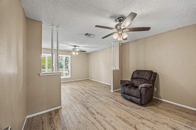 unfurnished room with ceiling fan, light hardwood / wood-style floors, and a textured ceiling