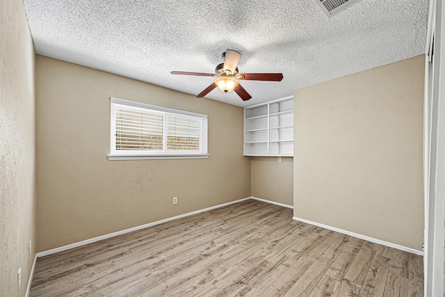 spare room with ceiling fan, light wood-type flooring, and a textured ceiling