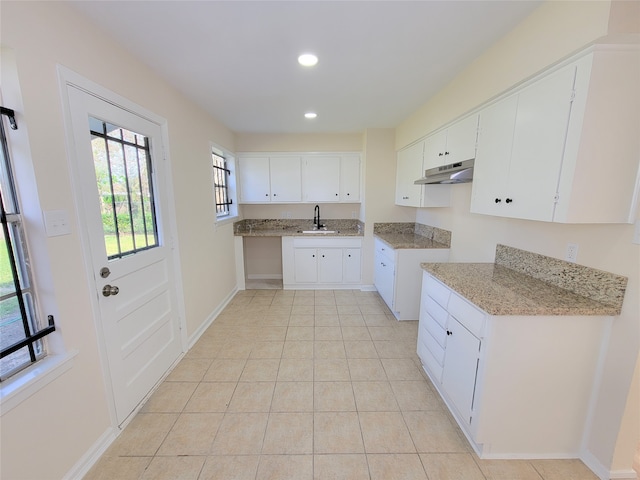 kitchen featuring light stone countertops, white cabinetry, sink, and light tile patterned floors