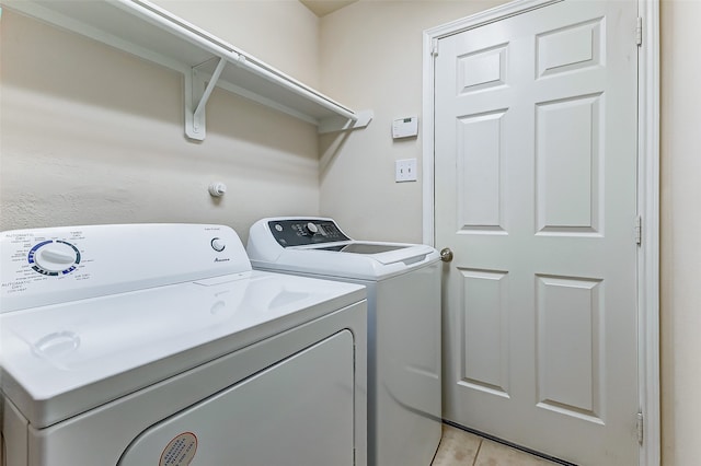 clothes washing area featuring light tile patterned flooring and washing machine and clothes dryer