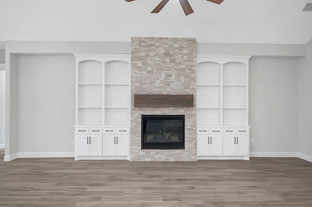 unfurnished living room featuring wood-type flooring, a fireplace, built in features, and ceiling fan