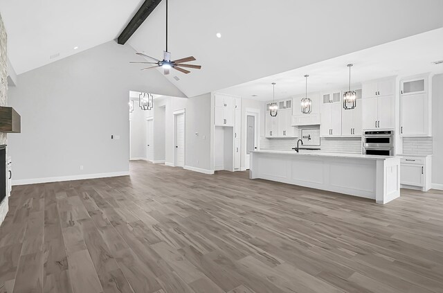 unfurnished living room with ceiling fan, beamed ceiling, dark hardwood / wood-style flooring, and high vaulted ceiling