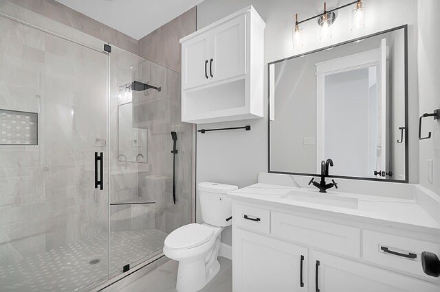 bathroom featuring a shower with shower door, vanity, and toilet