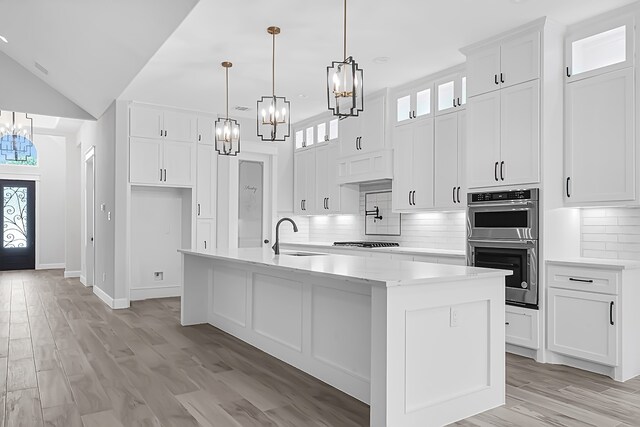 kitchen featuring pendant lighting, an island with sink, sink, white cabinetry, and stainless steel appliances