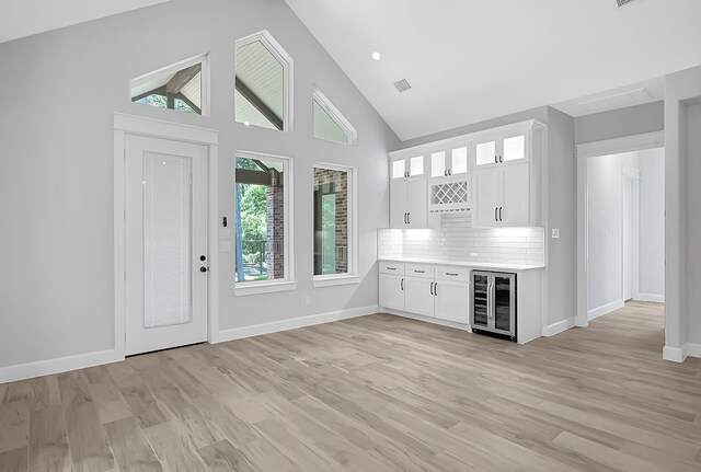 interior space with backsplash, wine cooler, light wood-type flooring, and white cabinetry