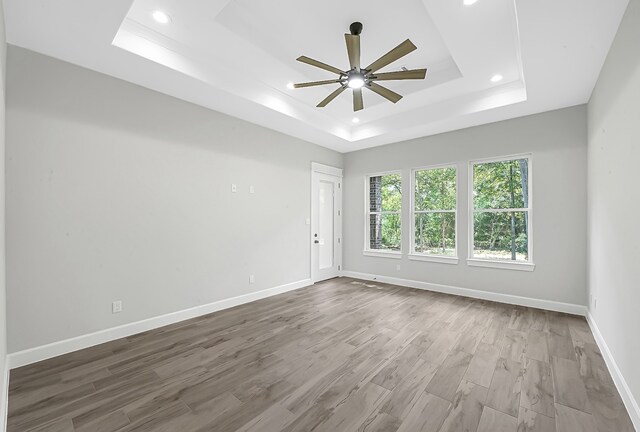 spare room featuring ceiling fan, hardwood / wood-style flooring, and a tray ceiling