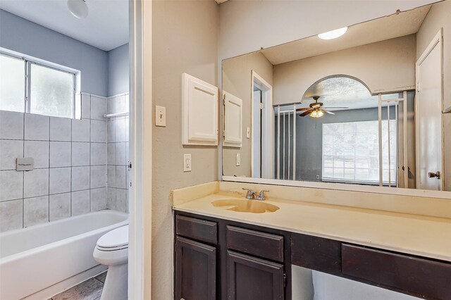 full bathroom featuring ceiling fan, tiled shower / bath, vanity, and toilet