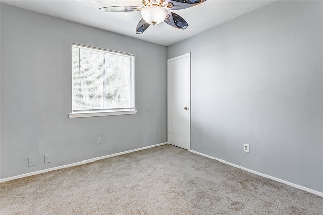 empty room featuring ceiling fan and light colored carpet